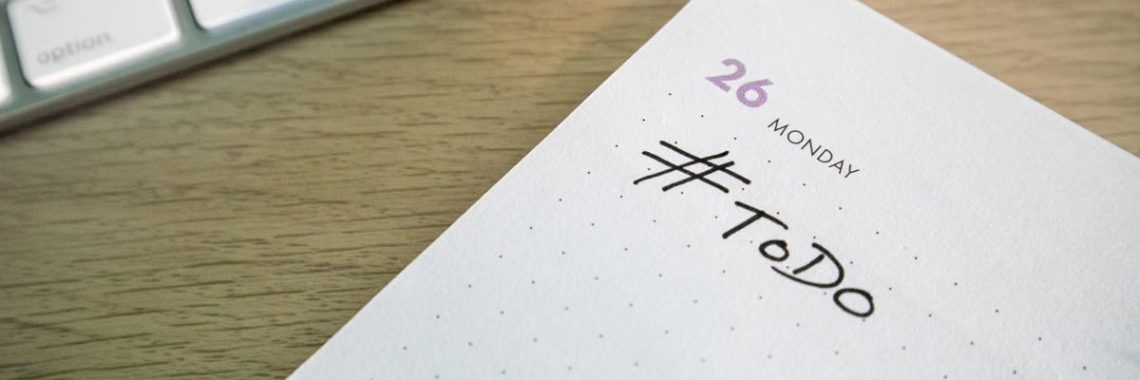 Close-up of a to-do list next to a computer keyboard on a desk.